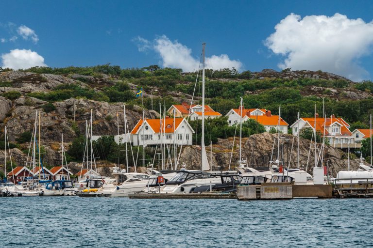 the-coastal-town-of-marstrand-in-southwest-sweden-houses-with-orange-roofs-sit-on-a-rocky-slope-a-large-number-of-sailboats-are-moored-in-the-foreground-2